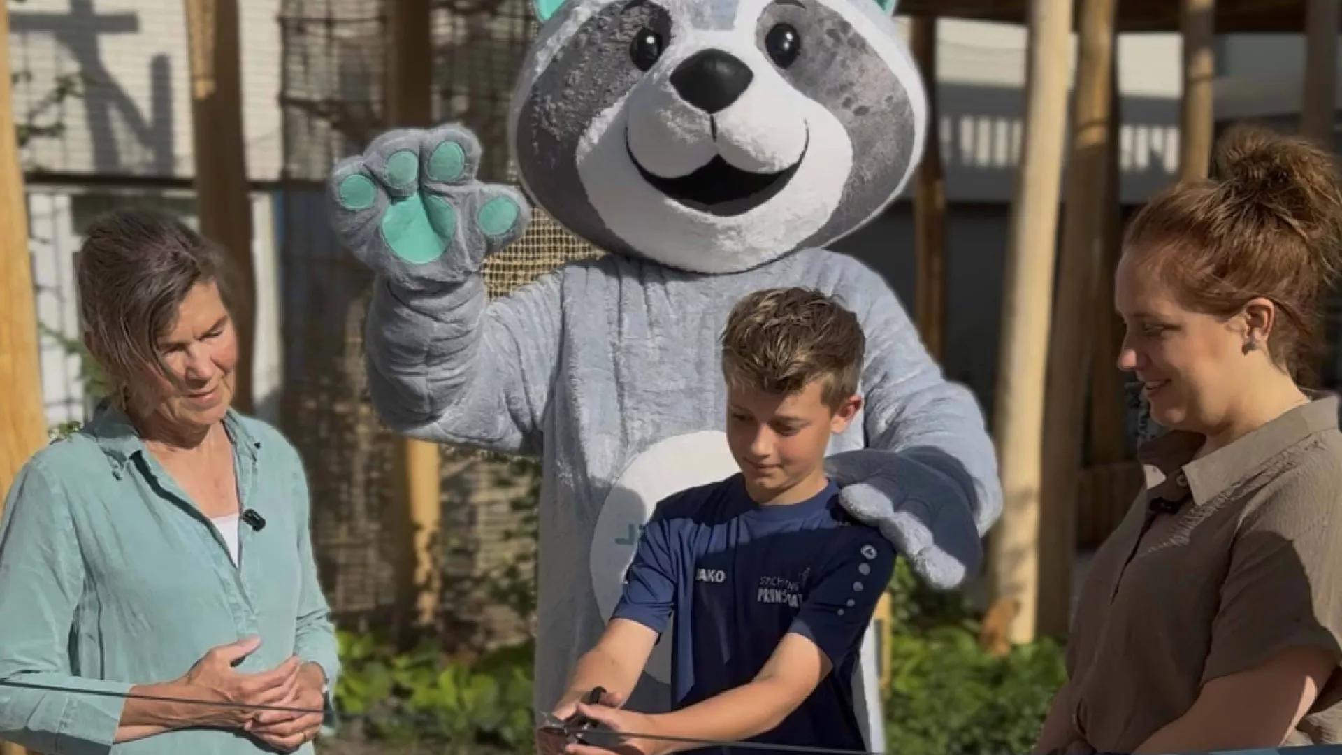 De speeltuin wordt officieel geopend door de zoon van Greta Prins samen met mascotte en twee volwassenen.