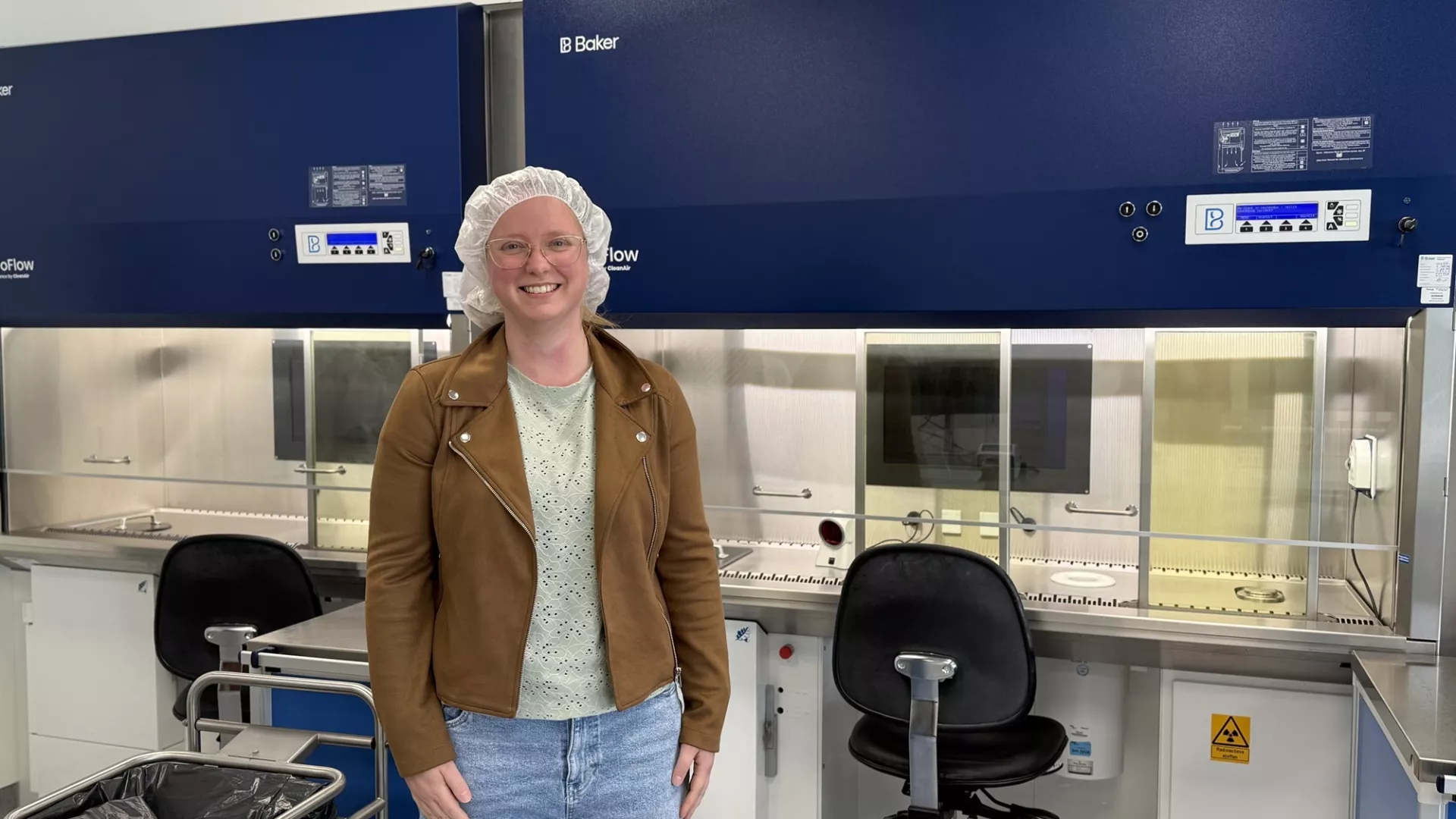 Persoon in laboratoriumomgeving met veiligheidskleding.