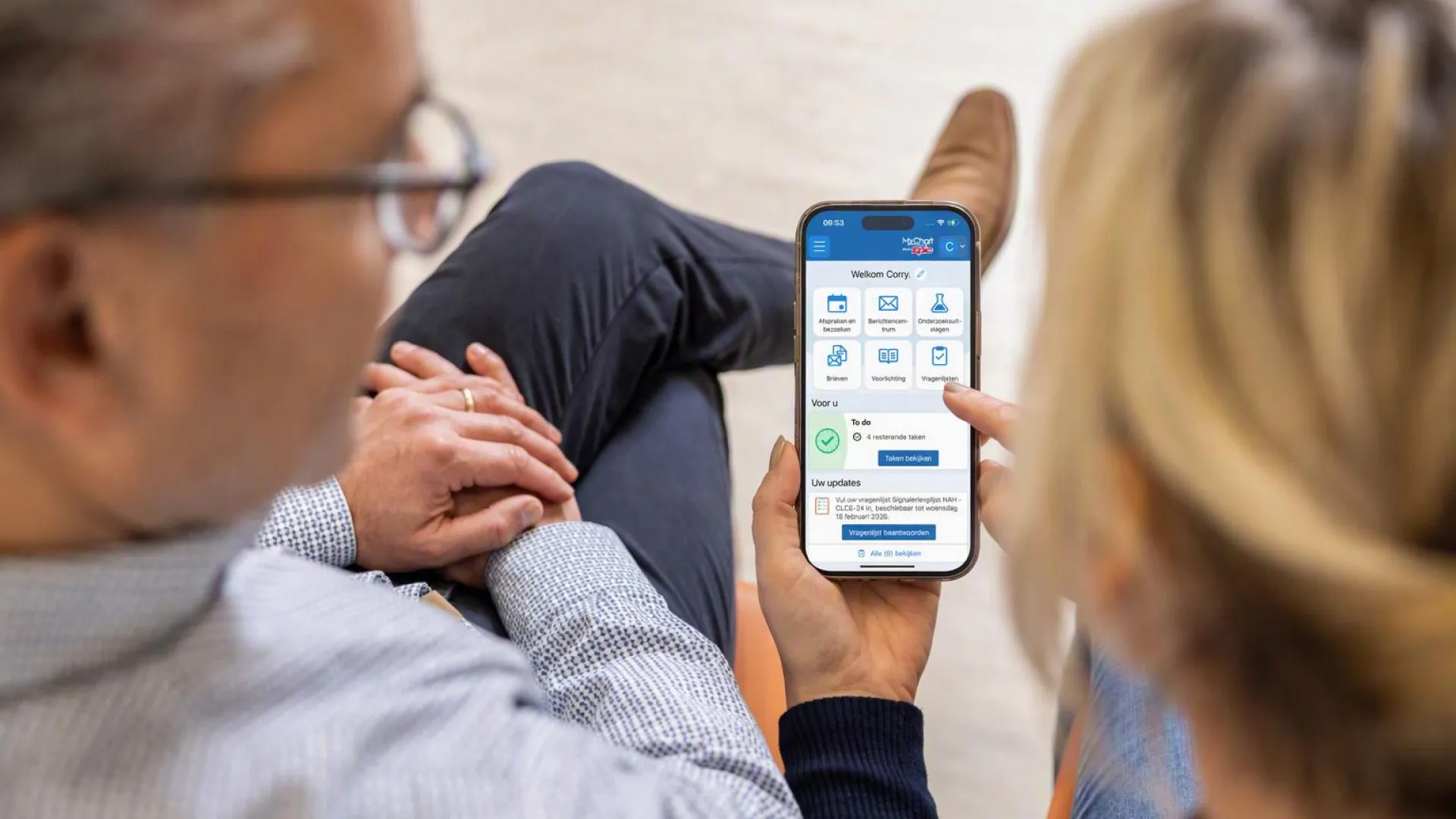Twee mensen bekijken samen mijnFrisiusMC op hun smartphone.