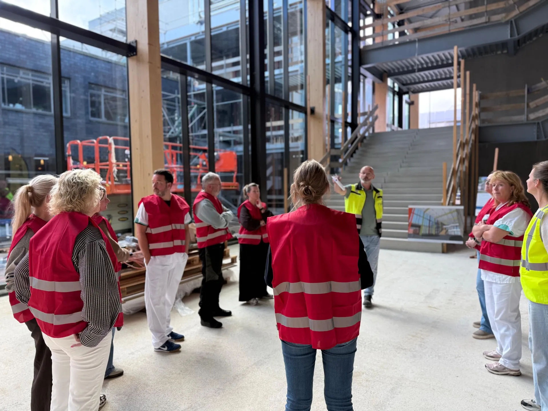 Een groep mensen in rode veiligheidshesjes is bijeen in de nieuwbouw van Frisius MC dat in aanbouw is.