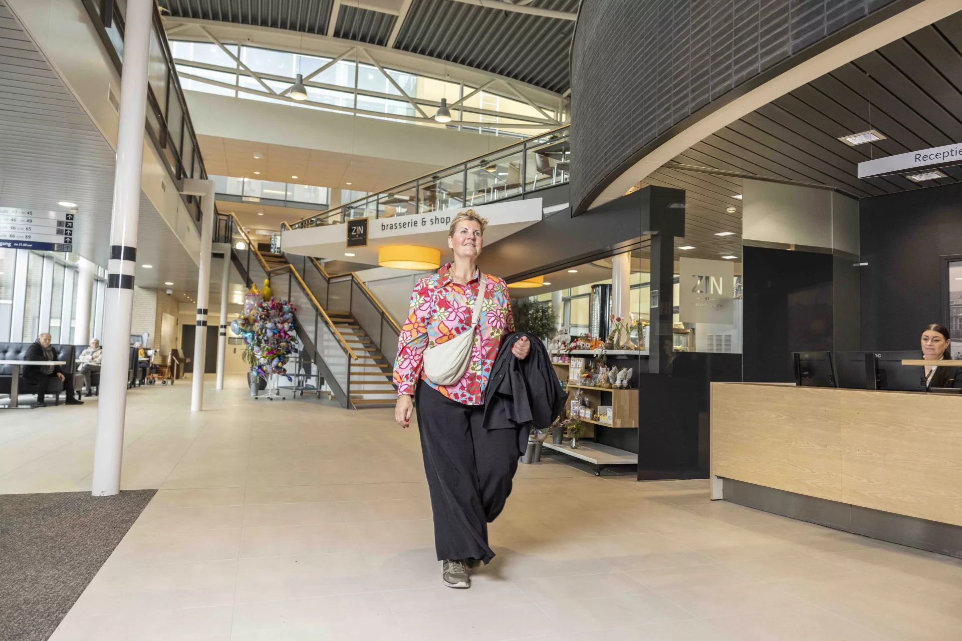 Een persoon loopt langs de receptie van het ziekenhuis.