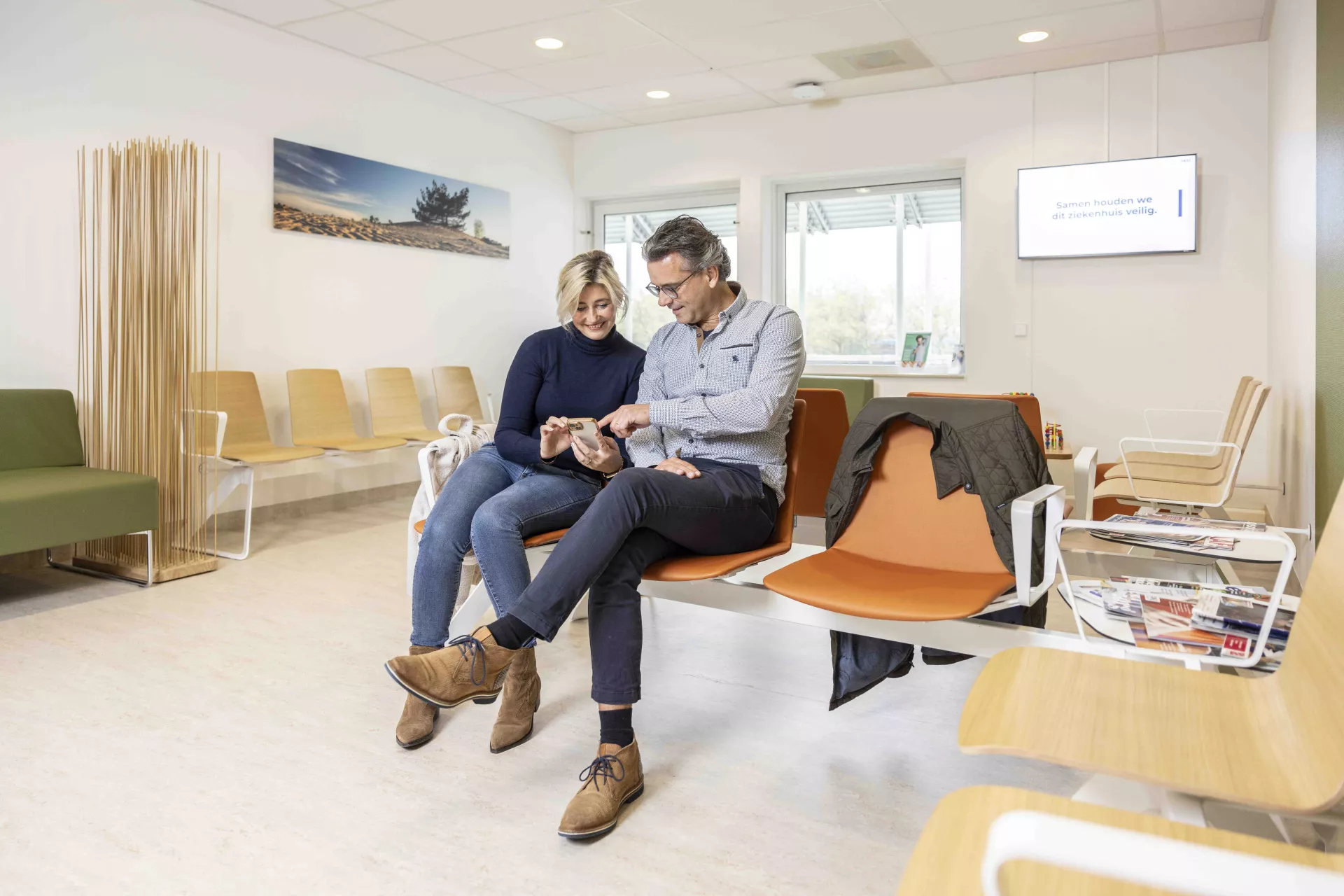 Een man en vrouw zitten samen te wachten in de wachtruimte.