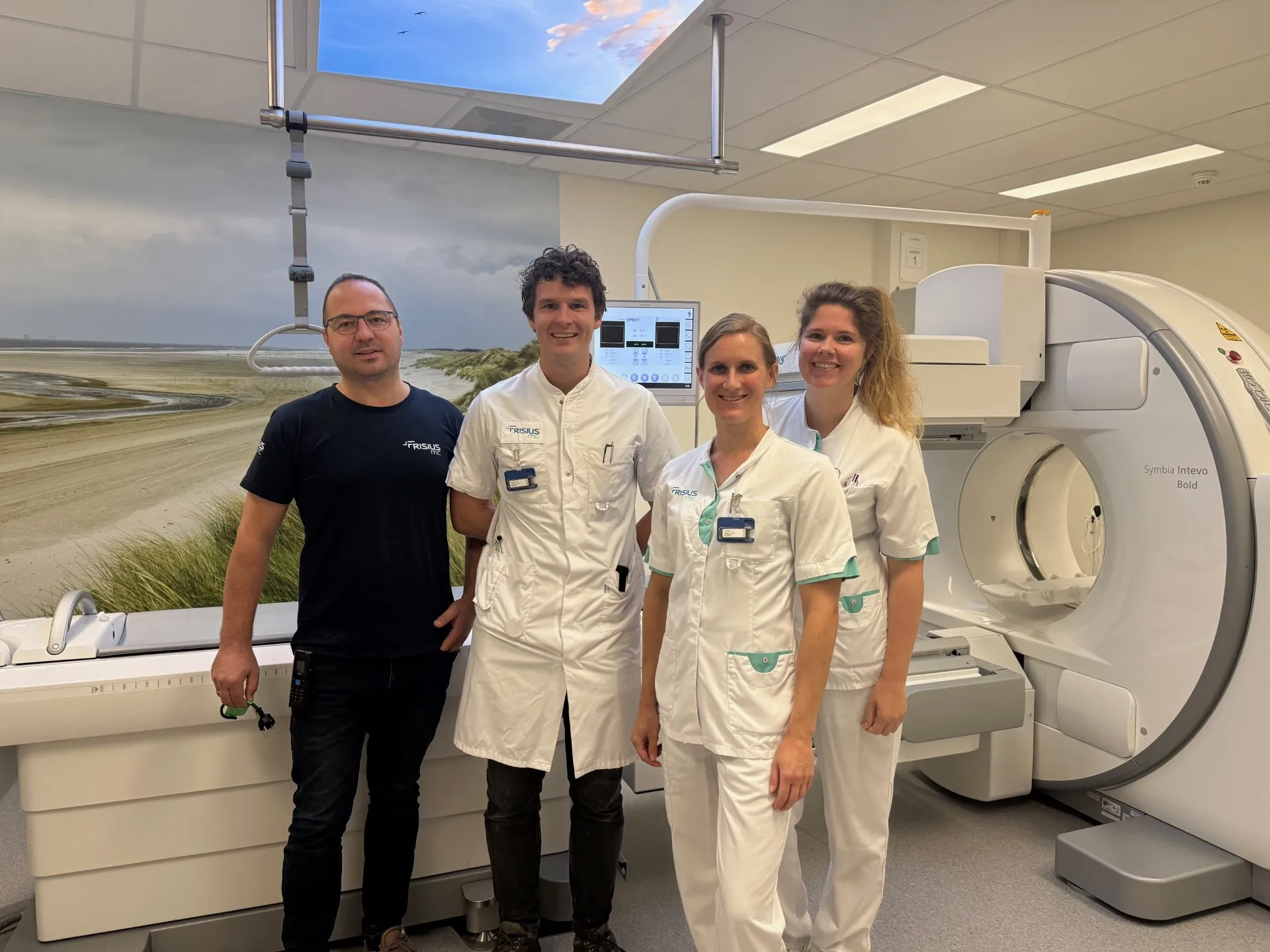 Vier mensen in een medische scanruimte poseren voor een CT-scanner.