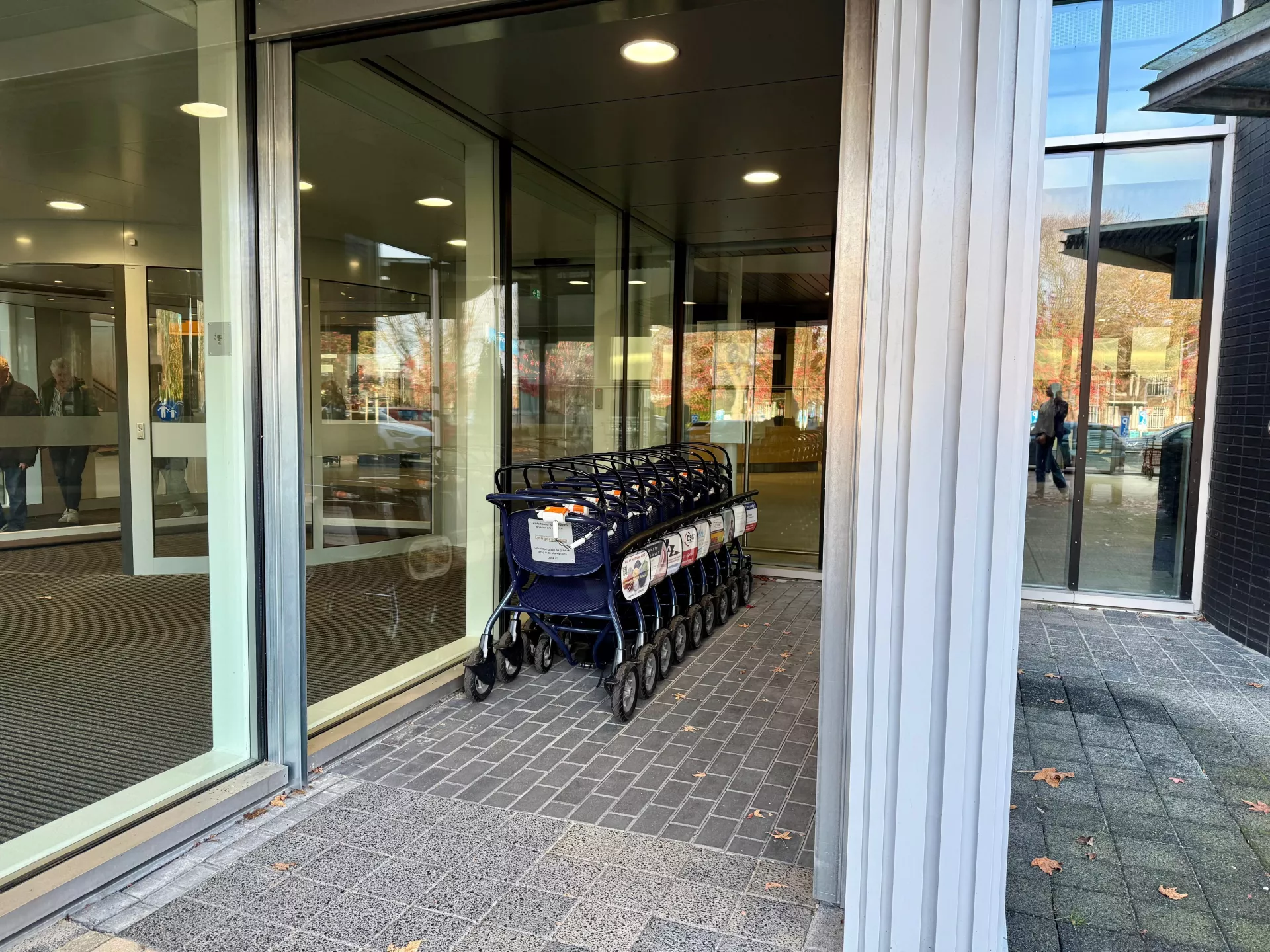 Een rij rolstoelen bij de ingang van het ziekenhuis.