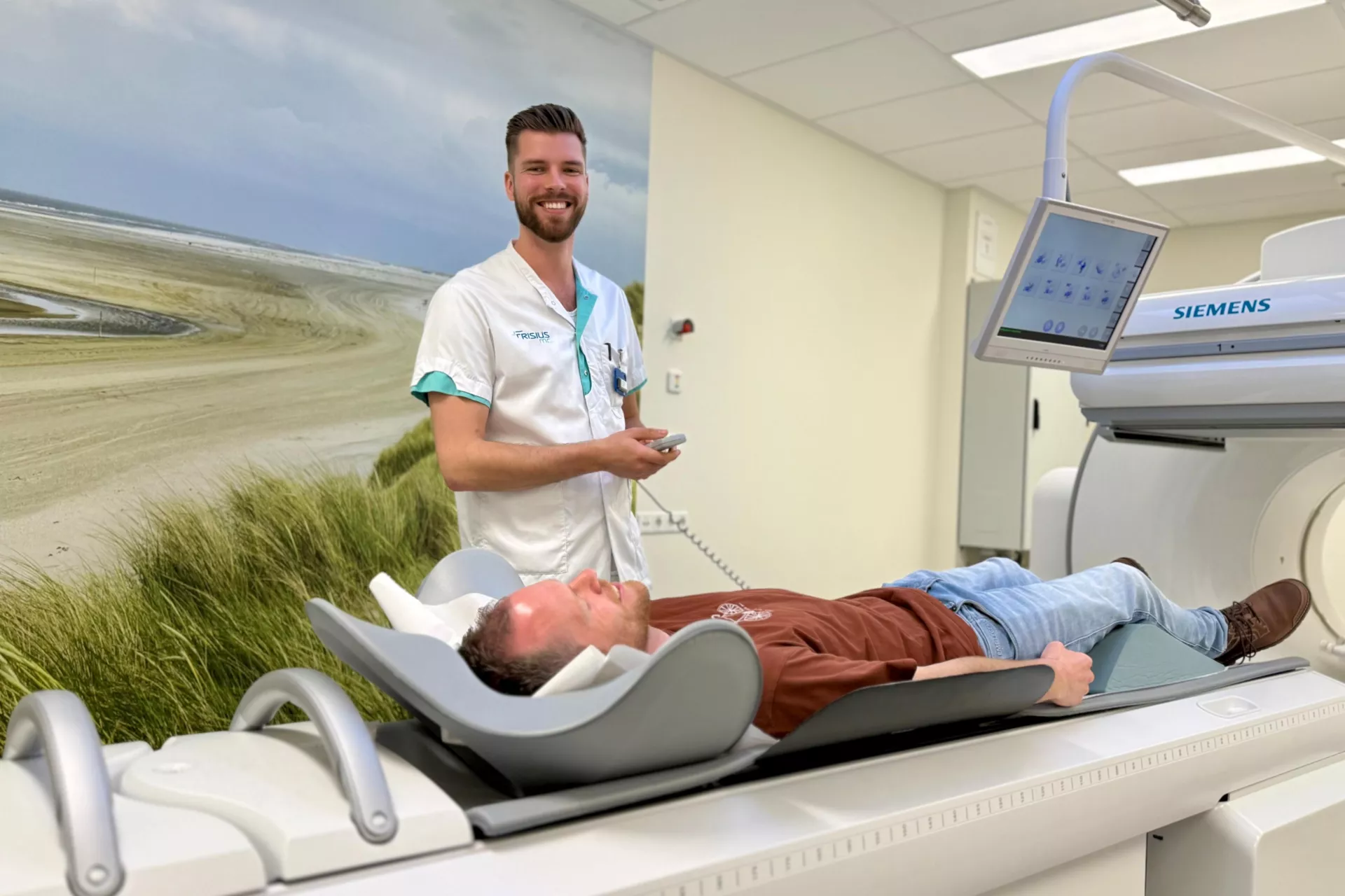 Een patiënt ligt klaar voor een MRI-scan terwijl een zorgverlener erbij staat en glimlacht.