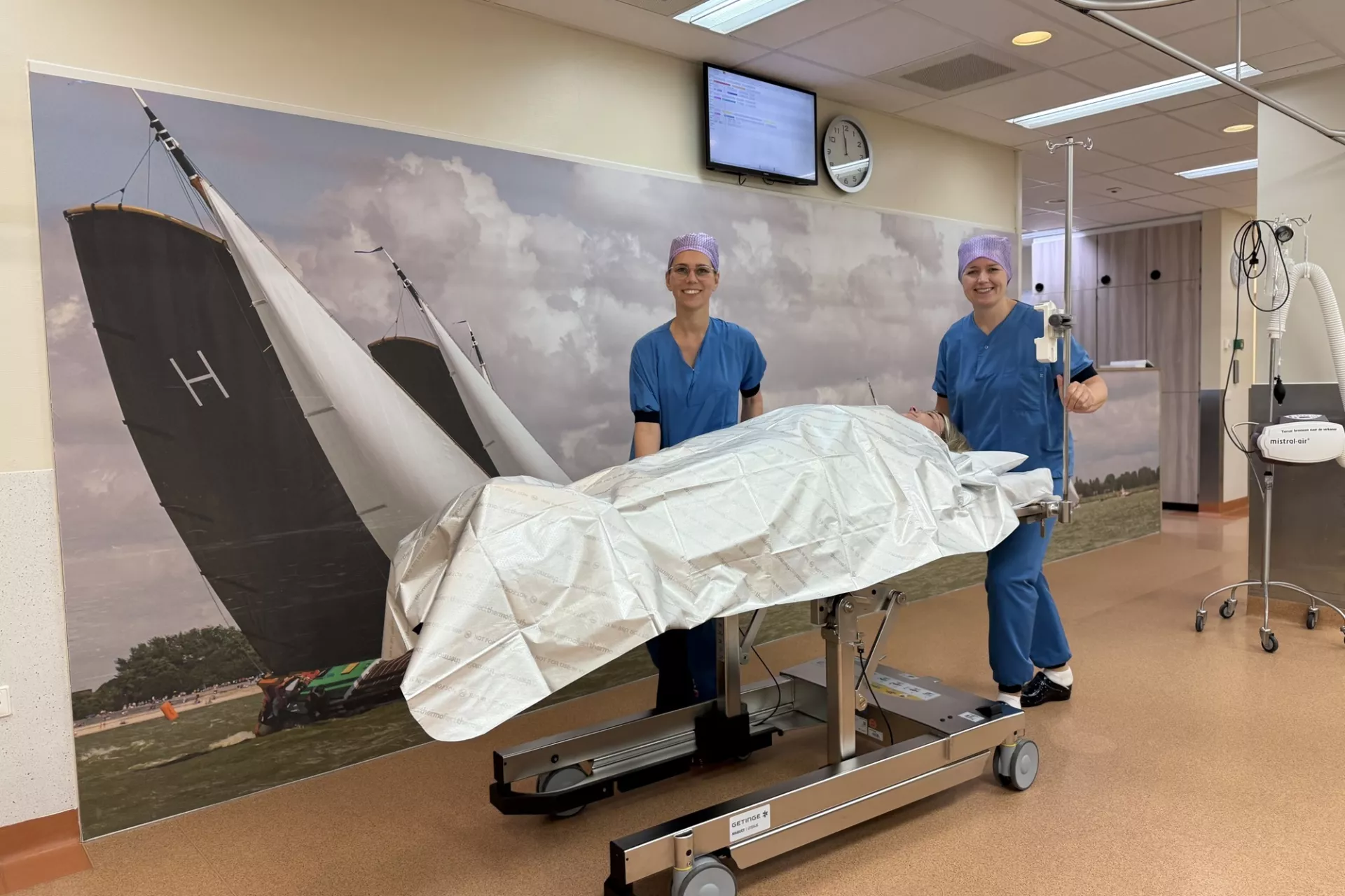 Twee chirurgen in een operatiekamer, met een bed gedekt met een laken.