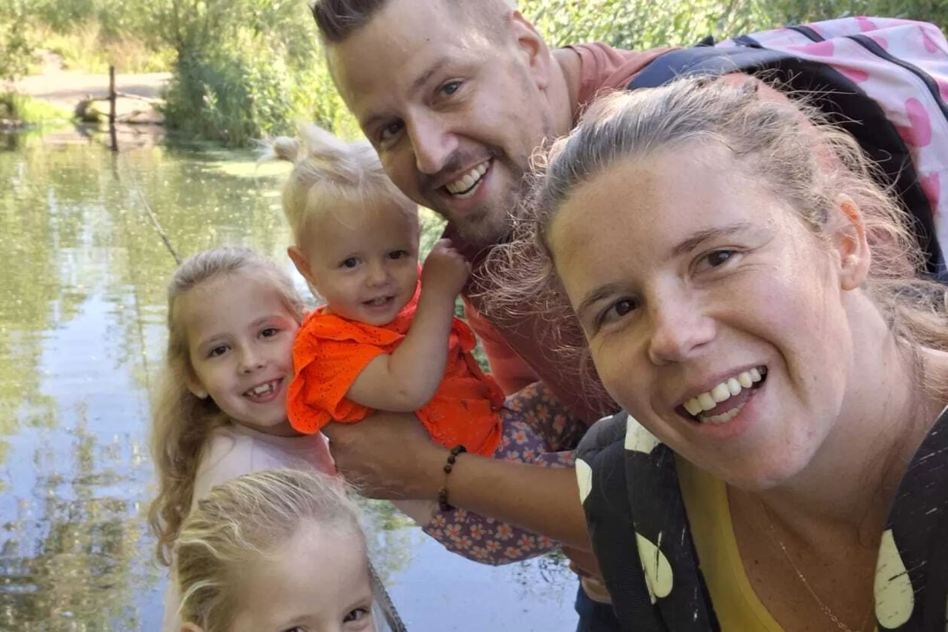 Een gezin poseert samen bij een rustige waterpartij.