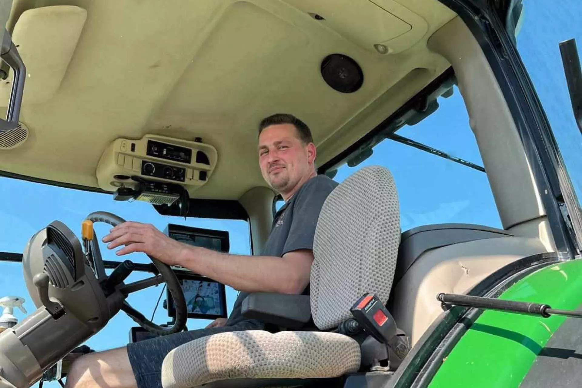 Een man zit achter het stuur van een tractor.