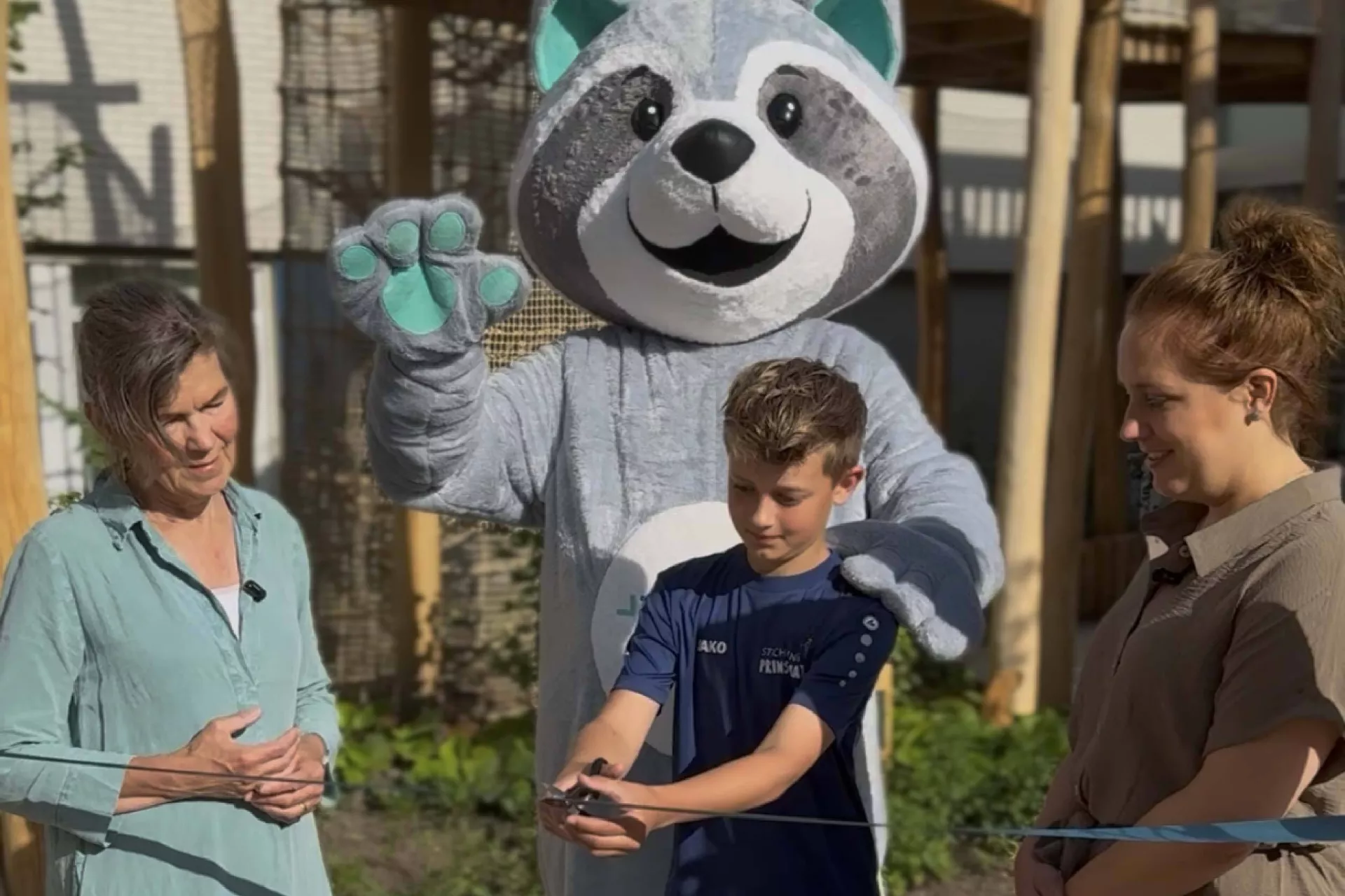 De speeltuin wordt officieel geopend door de zoon van Greta Prins samen met mascotte en twee volwassenen.