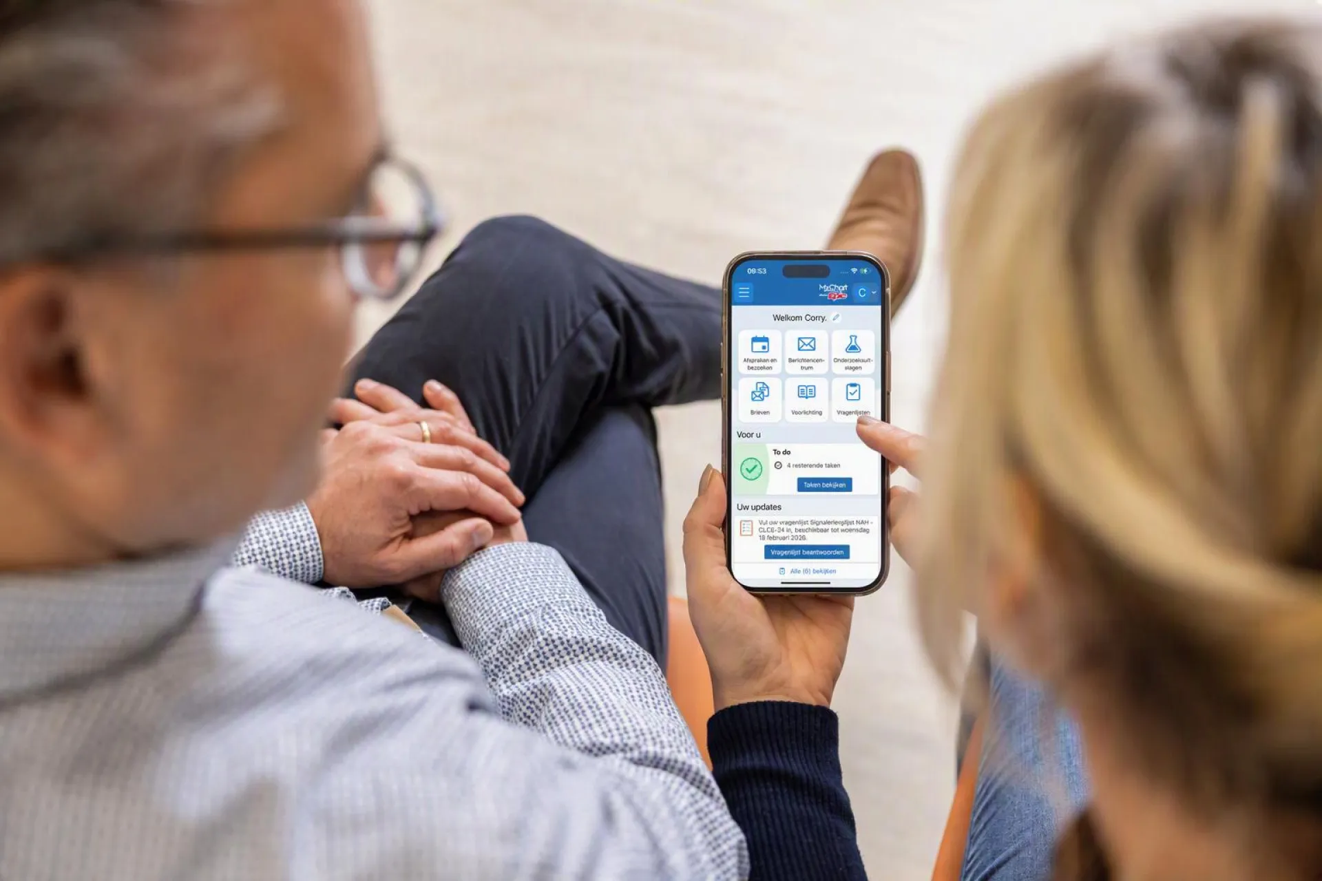 Twee mensen bekijken samen mijnFrisiusMC op hun smartphone.