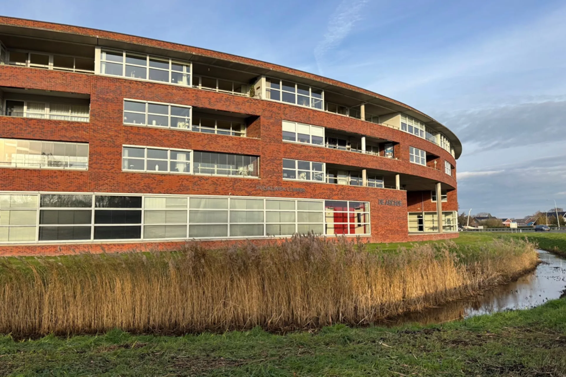 Aanzicht van een rond gebouw met bakstenen en grote ramen.