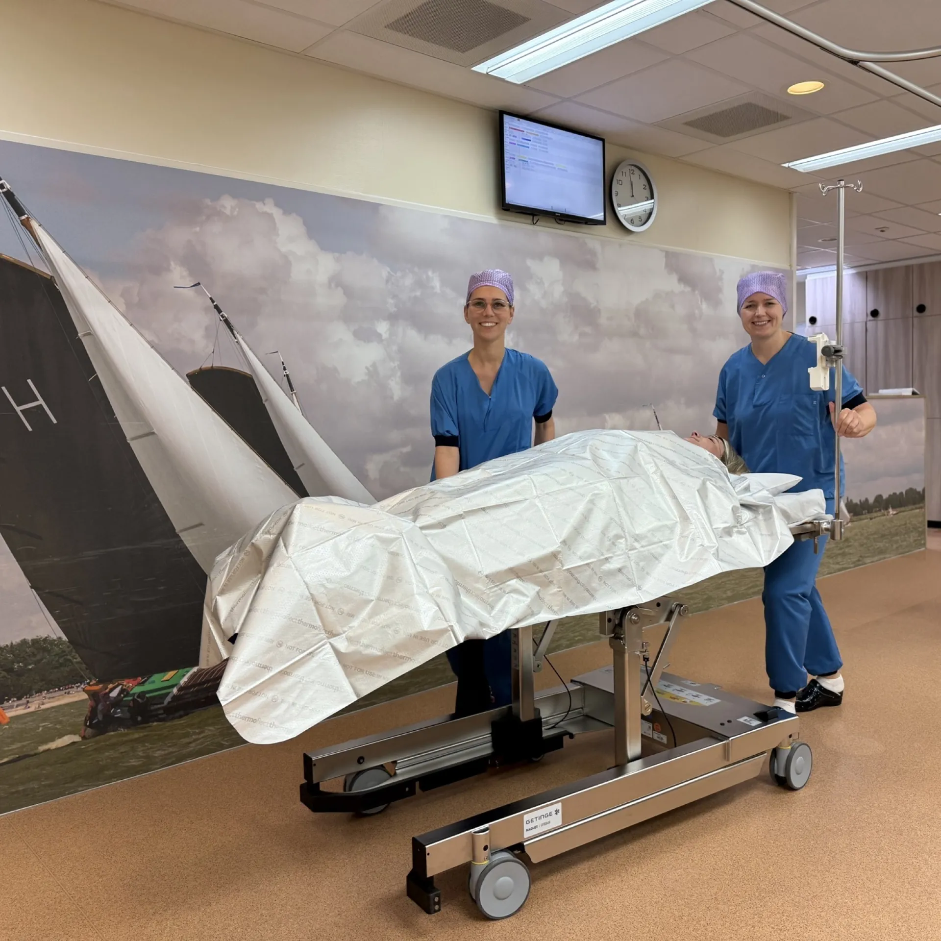 Twee chirurgen in een operatiekamer, met een bed gedekt met een laken.