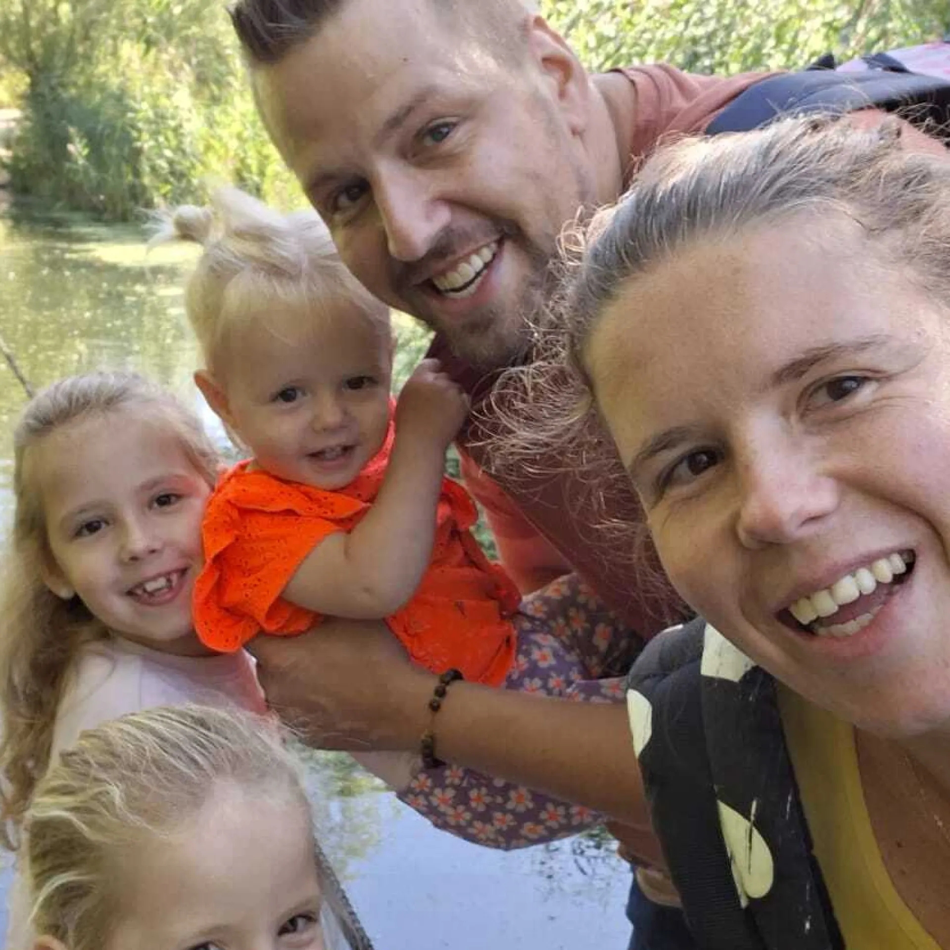 Een gezin poseert samen bij een rustige waterpartij.