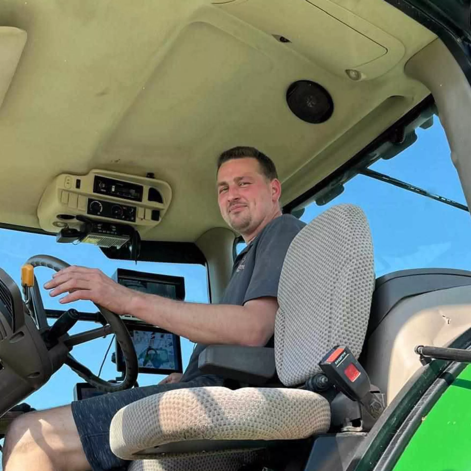 Een man zit achter het stuur van een tractor.